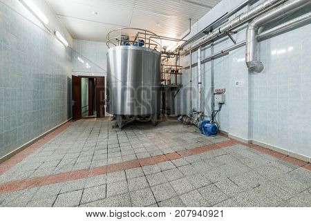 A large room with an installed metal cistern. Equipment for mixing sugar and yeast mixture.