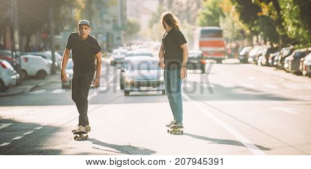 Two Pro Skateboard Rider Ride Skate Through Cars On Street