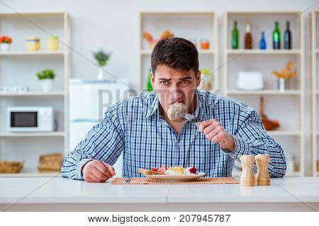Man eating tasteless food at home for lunch