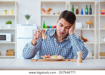 Young husband eating tasteless food at home for lunch