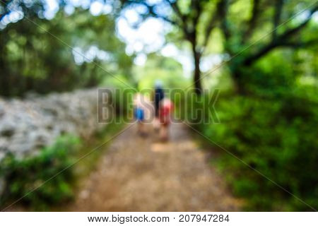 Family Hiking On Country Road With Rock Fence And Woods.