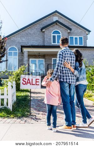 Family Looking At House On Sale