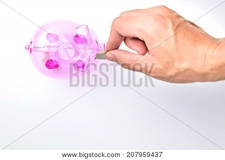 Hand Drop A Coin In Pinnk Piggy Bank on white background for money saving concept.