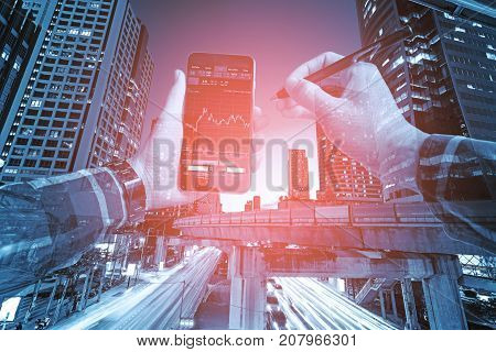 Double exposure of hands in hipster shirts holding smart phone for check stock market graph withlight of night building background Business Trading concept.