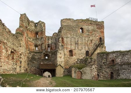 The ruins of the Livonia Order Castle was built in the middle of the 15th century. Bauska Latvia in autumn. Latvian flag on the top of the tower