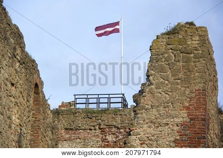 The ruins of the Livonia Order Castle was built in the middle of the 15th century. Bauska Latvia in autumn. Latvian flag on the top of the tower