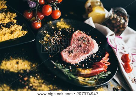 Food recipe for meat. Snack and vegetables as decoration. Tomatoes, olives, pepper on white napkin and spices scattered on black background. awesome