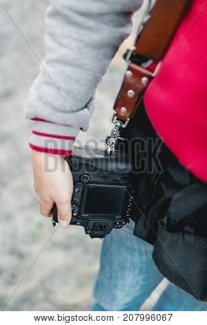 Photo camera on a leather strap. Photographer holds a camera in the hand. Close-up