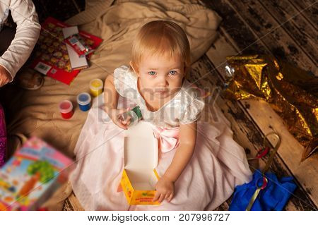 Portrait of adorable toddler girl sitting next to Christmas tree. Merry Christmas and Happy Holidays concept.