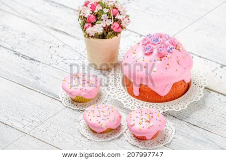 Traditional Easter cake with decorations and cupcakes on wooden table