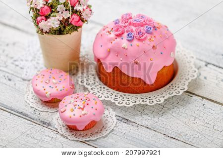 Traditional Easter cake with decorations and cupcakes on wooden table