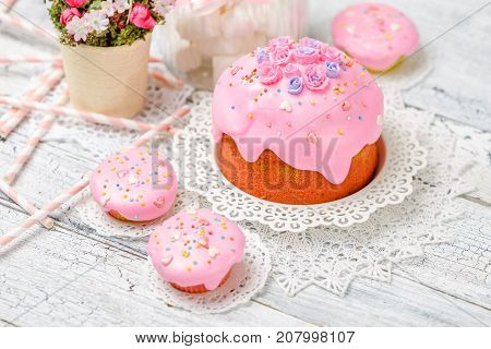 Traditional Easter cake with decorations and cupcakes on wooden table