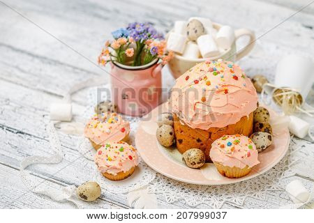 Traditional Easter cake with decorations and cupcakes on wooden table
