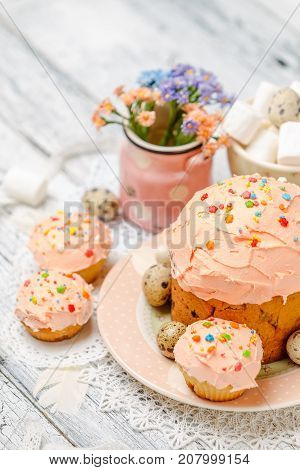 Traditional Easter cake with decorations and cupcakes on wooden table