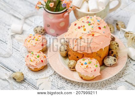 Traditional Easter cake with decorations and cupcakes on wooden table