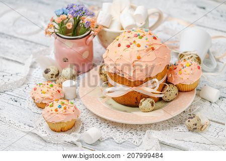 Traditional Easter cake with decorations and cupcakes on wooden table