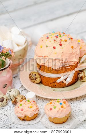 Traditional Easter cake with decorations and cupcakes on wooden table
