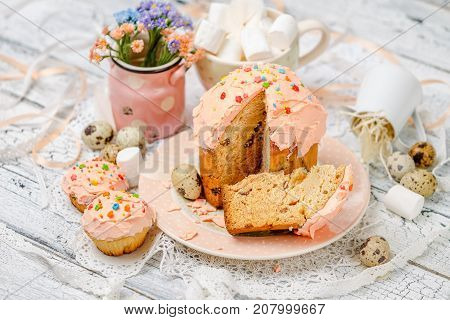 Traditional Easter cake with decorations and cupcakes on wooden table