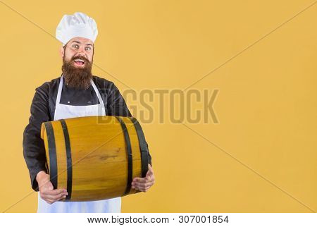 Smiling Seller Holds Wooden Barrel In Wine House. Man In Apron&hat Holds Whiskey Barrel In Distiller