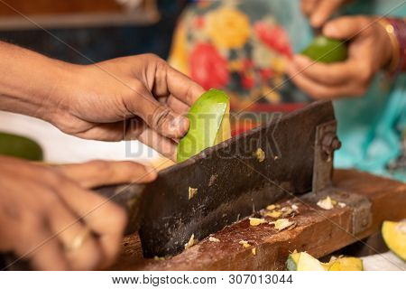 Closeuof Handing Cutting Ripe Mango For Making Picke In India With Indian Vegetable Cutter.