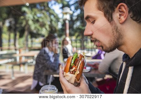 Hungry Guy Is Enthusiastically Looking At His Burger. He Is Sitting At The Restauraunt Terrace.