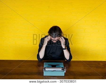 Man Writer In Black Shirt And Glasses, Stand With His Head Applied On A Typewriter On A Table Over Y