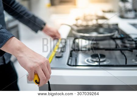 Male Hand Interior Designer Using Tape Measure On Gas Stove On Modern Countertop In Kitchen Showroom