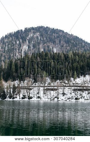 Lake Ritsa In Abkhazia In Spring. The Mountain Tops Are Covered With Snow. The Beginning Of The Tour
