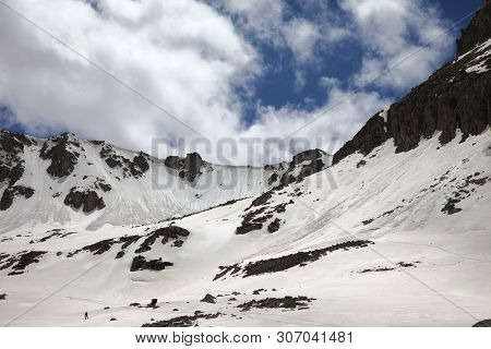 High Mountains With Snow Cornice And Avalanche Tracks, Snowy Plateau And Cloudy Sunlit Sky At Sunny 