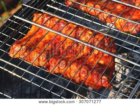 Slabs Smoked Pork Ribs Grilling On Barbecue Grid On Wooden Coals. Concept Background For A Family Su