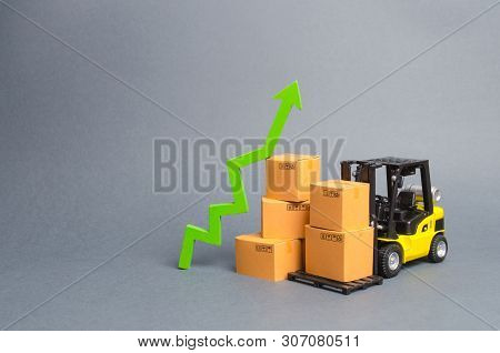 Yellow Forklift Truck With Cardboard Boxes And A Green Arrow Up. Growth Rate Of Production Goods And