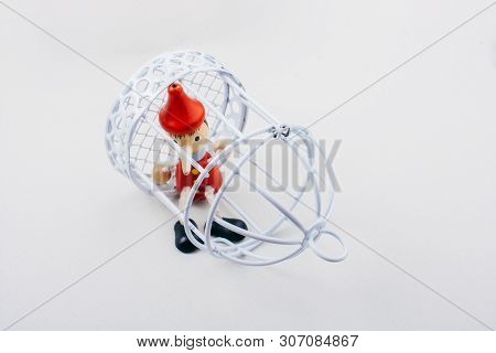 Metal Cage And Little Puppet Pinocchio Made Of Wood
