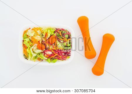 Fresh Vegetable Salad In Lunch Box With Orange Dumbbells Excercise Equipment On White. Active Health