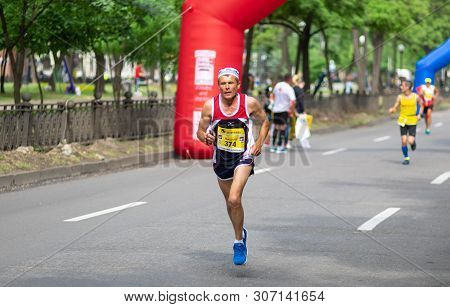 Dnipro, Ukraine - May 26, 2019: Senior Male Participant Running On A Dmytra Yavornitskoho Avenue Dur