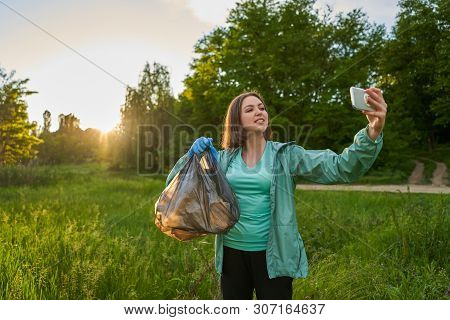 Blogging Concept. The Girl Collects Trash From The Forest In The Trash Bag