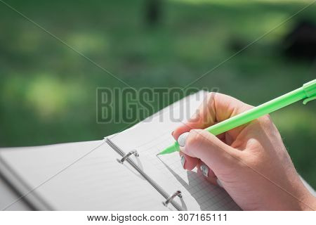 Girls Hands With Pen Writing On Notebook In Urban Park Summer Day
