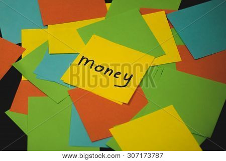 The Word Money On A Piece Of Yellow Paper Among Multicolored Paper