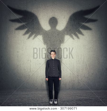 Casual Confident Woman Full Length Portrait Casting A Superhero Shadow With Angel Wings On A Dark Ro