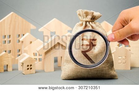 Money Bag With A Sign Indian Rupee (rupiah) And Wooden Houses. The Concept Of Real Estate Market. Pr