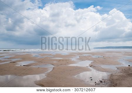 Minimalist Image Of A Flat Sandy Beach At Filey, North Yorkshire, With Numerous Puddles Left Behind 