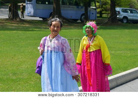 Pyongyang, North Korea - May 1, 2019: An Old Women In Traditional Korean Clothes Walking In The Taes