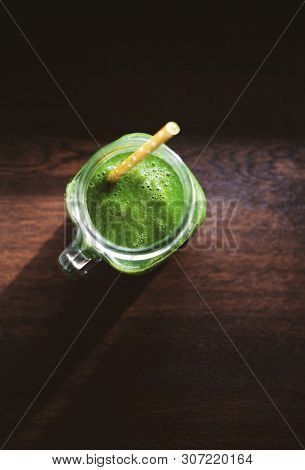 jar with green cold-pressed juice, wooden background. Healthy eating, detoxing, juicing body cleancing concept 