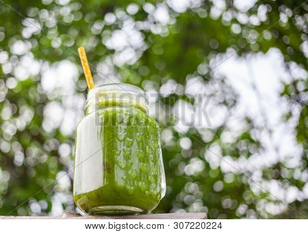  a jar with green cold-pressed juice, nature background. Healthy eating, detoxing, juicing, body cleancing concept 