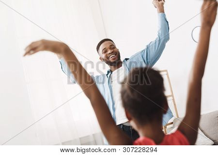 Little Afro Daughter Teaching Dad To Dance In Modern Style At Home, Having Fun Together