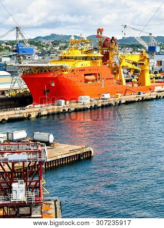 A Large Orange And Yellow Colored Offshore Construction Vessel (ocv) Is In A Dry Dock Of A Shipyard 