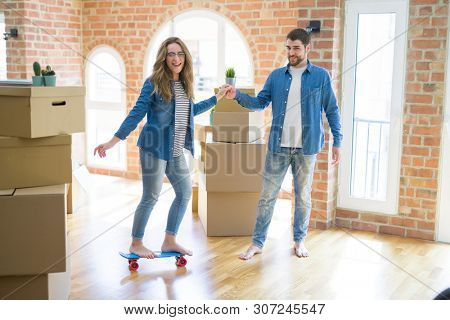 Young couple moving to a new home, having fun riding a skateboar