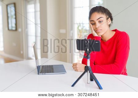 Young african american woman doing video call using smartphone camera thinking looking tired and bored with depression problems with crossed arms.