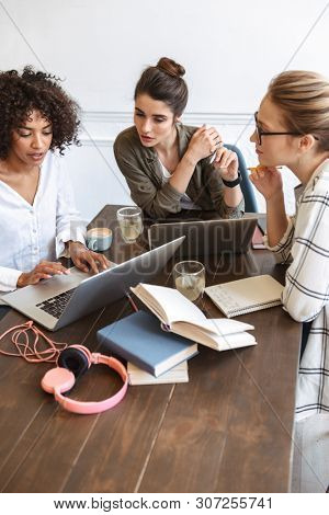 Group of multiethnic cheerful young women studying together at the coffee shop