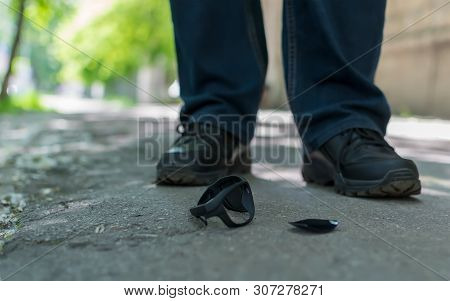 View Of The Feet Of A Man Who Stands On An Asphalt Road On The Background Of Fallen And Broken Sun G
