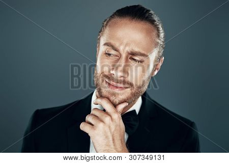 Something On His Mind... Charming Young Man In Bow Tie Looking Away And Keeping Hand On Chin While S